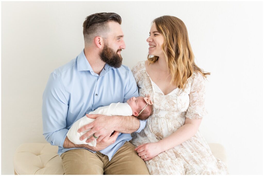 Mom and Dad holding newborn baby girl swaddled 