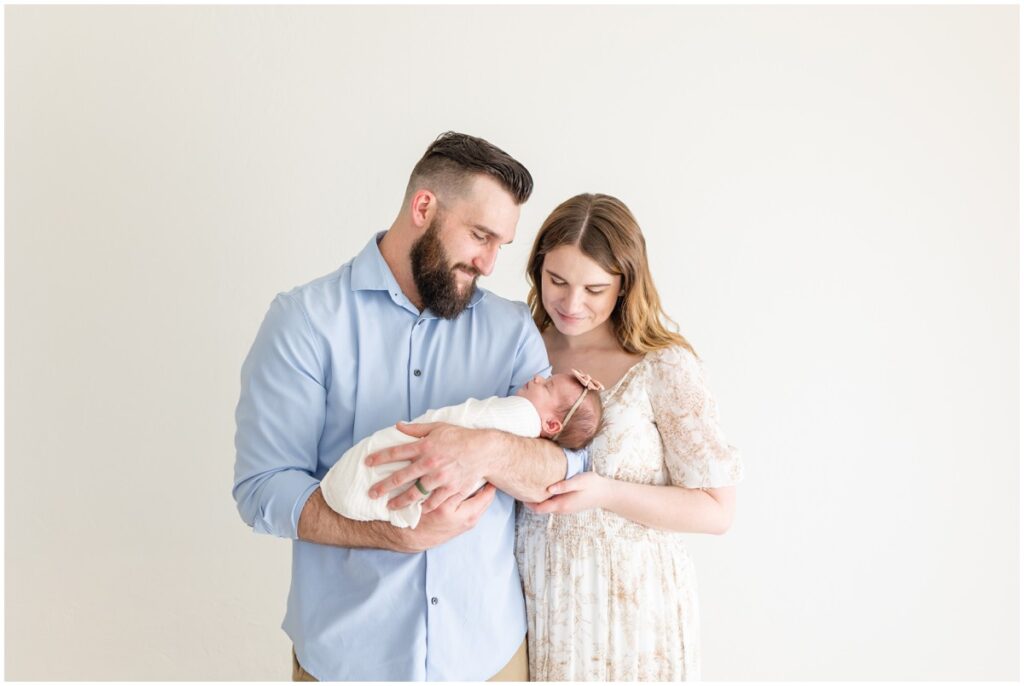 Mom and Dad holding newborn baby girl swaddled 