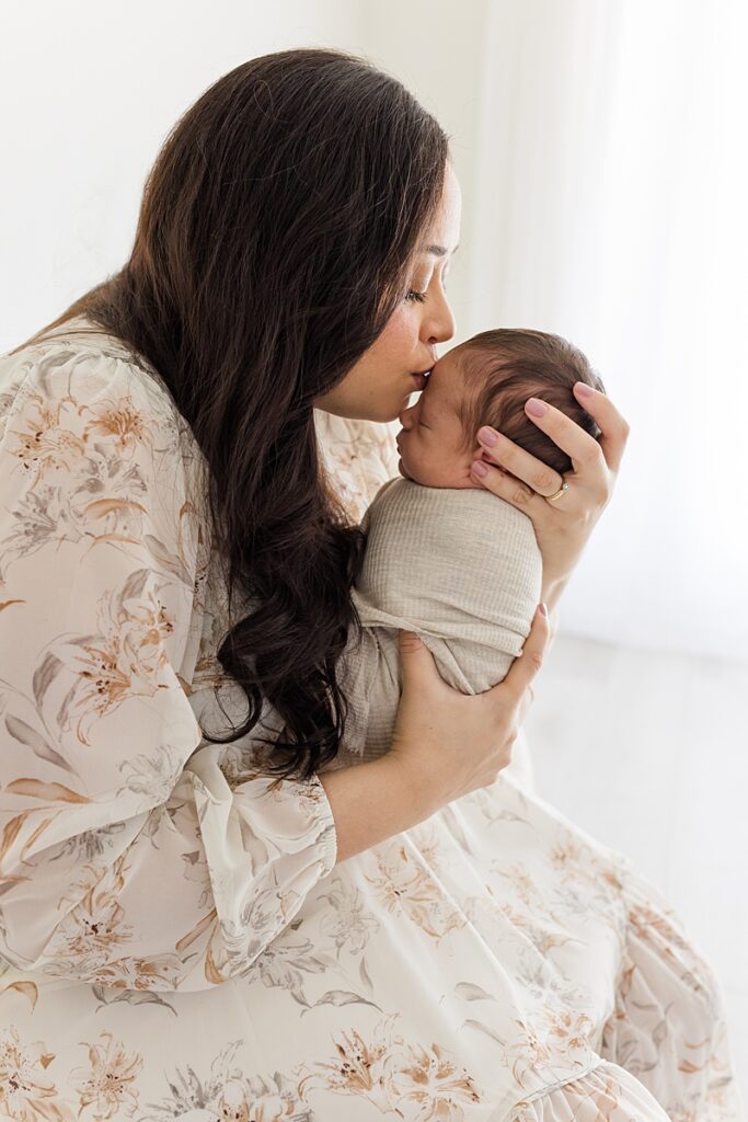 mother holding swaddled newborn in okc newborn photographer studio