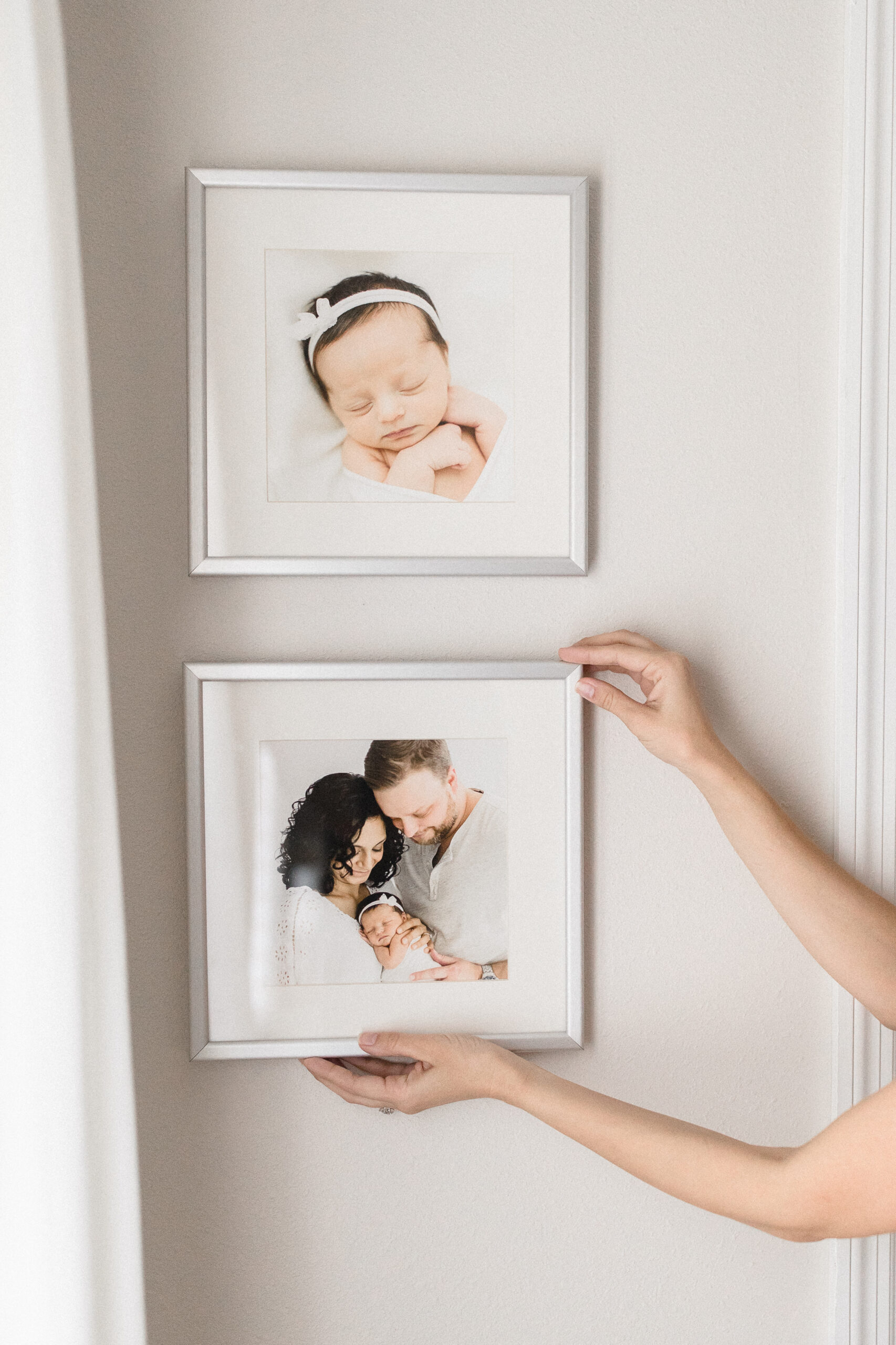 OKC Newborn photographer hanging frames on wall.